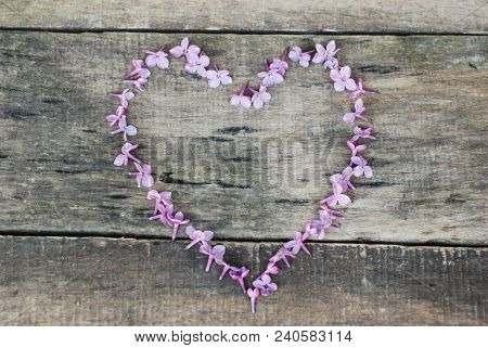 Spring Flowers. Lilac Flowers Frame Heart Shape Textured Rustic Gray Wooden Background.