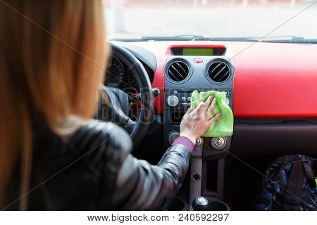 A Young Woman Wipes The Dust With A Green Rag In The Car. Dry Cleaning Of The Car Panel, Car Washing