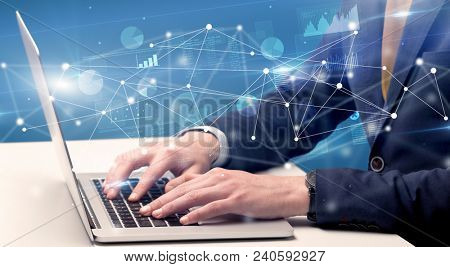 Businessman typing on laptop with linked reports charts grapghs around