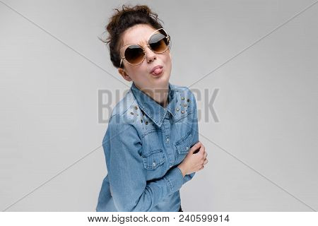 Young Girl In Black Cat Glasses On A Gray Background. Portrait Of A Young Beautiful Girl. Charming G