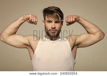 Man Flex Muscles, Biceps, Triceps On Grey Background. Macho With Strong Arms In White Singlet. Worko