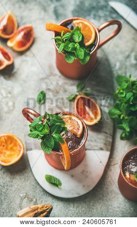 Blood Orange Moscow Mule Alcohol Cocktails With Fresh Mint Leaves And Ice In Copper Mugs On Board In