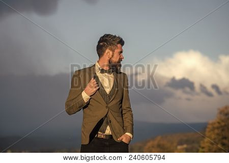 Hipster With Stylish Appearance In Front Of Dramatic Sky. Man With Beard And Mustache With Scenery O