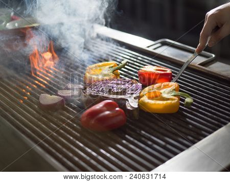 Master chef cooking delicious grilled meat steak with vegetables on a barbecue