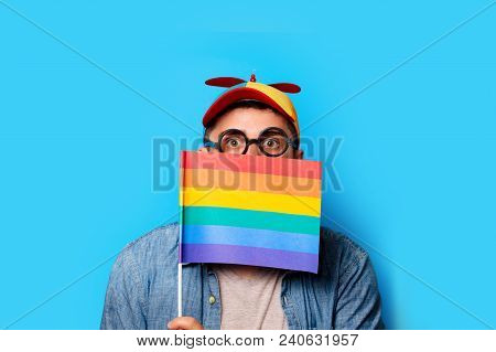 Young Nerd Man With Noob Hat Holding A Rainbow Flag On Blue Background