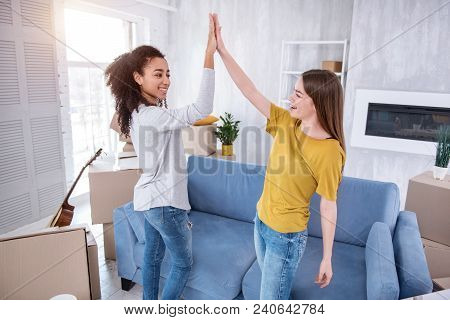 Great Job. Upbeat Young Girls Giving Each Other A High Five After Finishing Unpacking Of A Significa