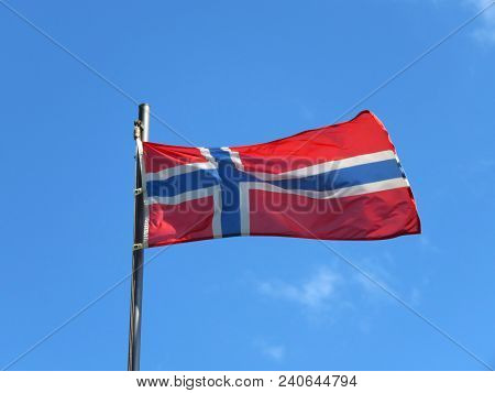 National Flag Of Norway On A Flagpole In Front Of Blue Sky.
