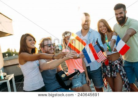 Group Of People Holding National Flags And Having Fun On Rooftop