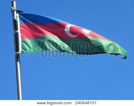 National Flag Of Azerbaijan On A Flagpole In Front Of Blue Sky.