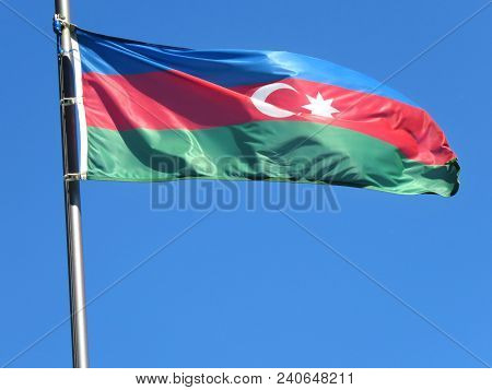 National Flag Of Azerbaijan On A Flagpole In Front Of Blue Sky.