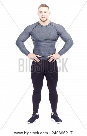 Portrait Of Handsome Well-muscled Gym Instructor In Sports Tights And Rashguard Posing On White Back