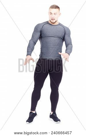 Portrait Of Handsome Well-muscled Gym Instructor In Sports Tights And Rashguard Posing On White Back