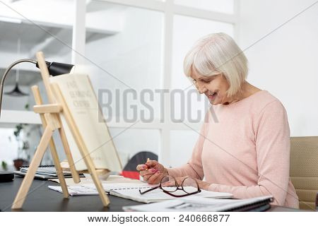 Eager For Knowledge. Pleased Senior Woman Studying While Making Records