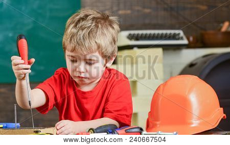Closeup Blond Kid In Workshop. Boy Binding Screws To Wooden Board. Concentrated Child Learning New S