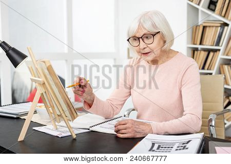 Useful Task. Energetic Senior Woman Studying While Pointing At Book