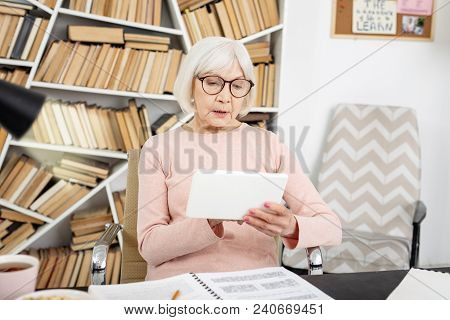 Distance Learning. Appealing Senior Woman Using Tablet While Sitting At Table