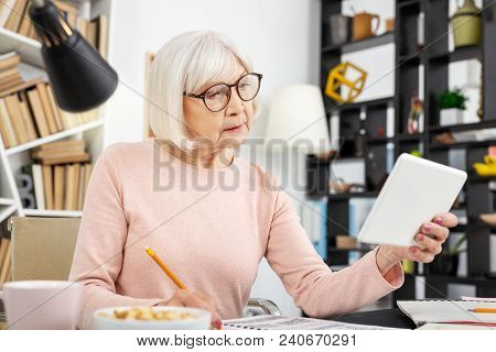 Education Online. Beautiful Senior Woman Using Tablet While Noting