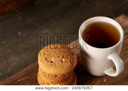 White Porcelain Mug Of Black Tea Or Earl Grey And Pile Of Sweet Cookies On Flat Piece Of Wood Over R