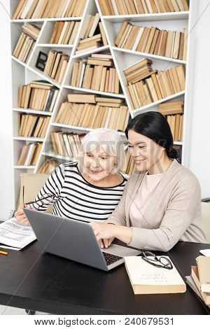 Technology In Study. Joyful Tutor And Mature Student Smiling And Staring At Screen