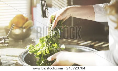 A Woman Cooks And Washes Greenery, Neetle In The Kitchen Under A Silver Clean Faucet, Water From A F