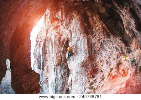 A Man Climbs The Rock. Rock In The Form Of An Arch. Cave. Fitness Outdoors. Extreme Sports. The Athl