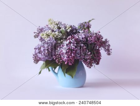 Beautiful Bouquet Of Fragrant Purple Flowers In Blue Ceramics Vase On Light Background. Syringa Vulg