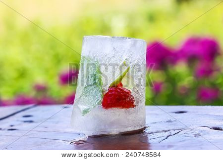 Melting Ice Cube With Strawberry, Lemon And Fresh Green Mint Leaves On Wooden Surface Outdoors