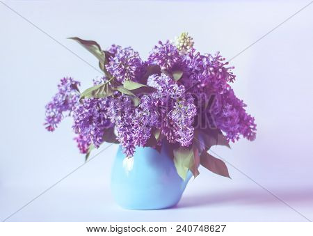 Beautiful Bouquet Of Fragrant Purple Flowers In Blue Ceramics Vase On Light Background. Syringa Vulg