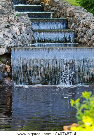 Cold Transparent Water Of Decorative Artificial Waterfall In Summer Park.
