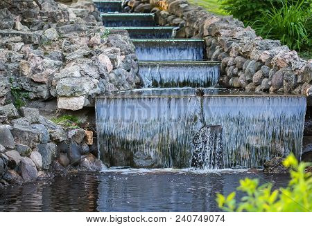 Cold Transparent Water Of Decorative Artificial Waterfall In Summer Park.