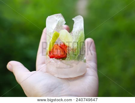 Melting Ice Cube With Strawberry, Lemon And Fresh Green Mint Leaves In A Hand