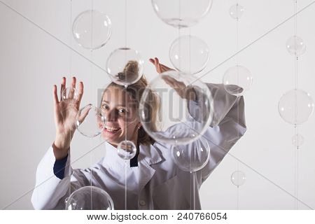 A Mad Scientist Is Experimenting With Glass Balls. A Woman In A White Robe Smiles Strangely And Stre