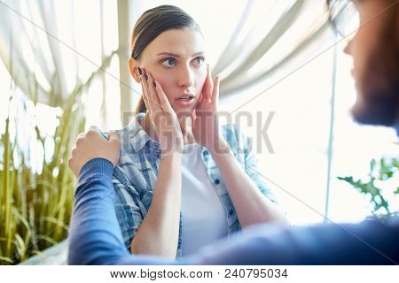 Young woman have a meeting with man at cafe. She's scared of something