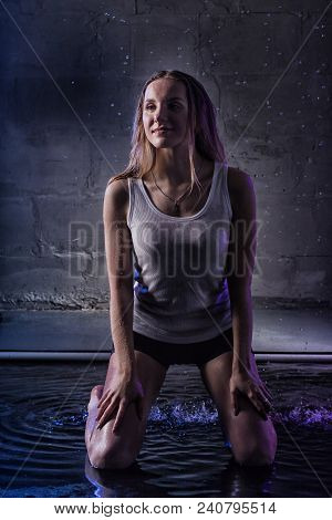Girl In The White Shirt With Water Drop In A Dark Room Illuminated By Light During A Photoshoot With