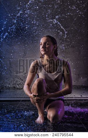 Girl In The White Shirt With Water Drop In A Dark Room Illuminated By Light During A Photoshoot With