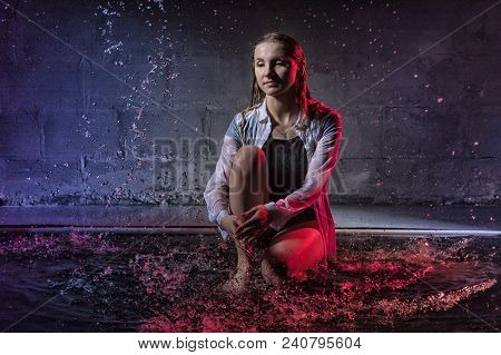 Girl In The White Shirt With Water Drop In A Dark Room Illuminated By Light During A Photoshoot With