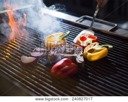 Master chef cooking delicious grilled meat steak with vegetables on a barbecue