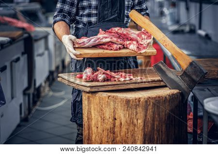 Bearded Butcher Dressed In A Fleece Shirt Serving Fresh Cut Meat In A Market.