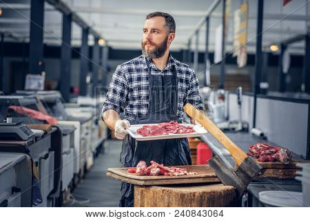 Bearded Butcher Dressed In A Fleece Shirt Serving Fresh Cut Meat In A Market.
