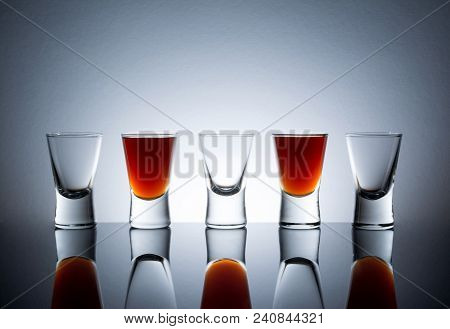 Small Glasses With A Drink Shots Of Alcohol Stainding In A Table With Reflection