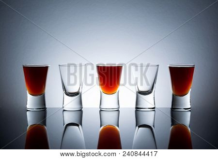 Small Glasses With A Drink Shots Of Alcohol Stainding In A Table With Reflection