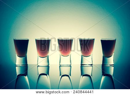 Small Glasses With A Drink Shots Of Alcohol Stainding In A Table With Reflection