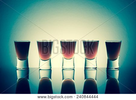 Small Glasses With A Drink Shots Of Alcohol Stainding In A Table With Reflection