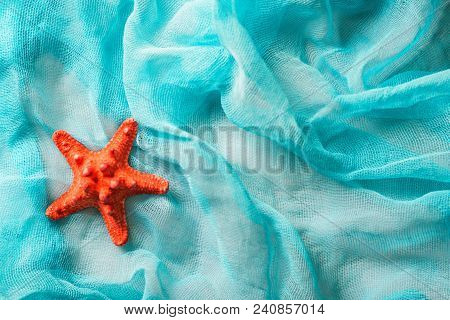 Close Up Bright Red Dried Starfish On Cian Cloth Surface. Summer Holiday Concept
