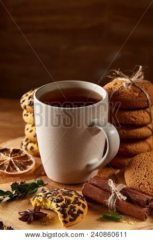 Christmas Concept With A Cup Of Hot Tea, A Large Set Of Cookies On A Homespun Napkin, Cinnamon Stick