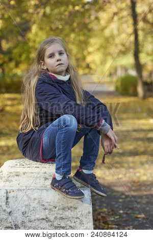 A Girl In Autumn Yellow Leaves In Sunset Rays