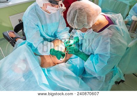 Surgeons Team Working With Patient In Surgical Operating Room. Breast Augmentation