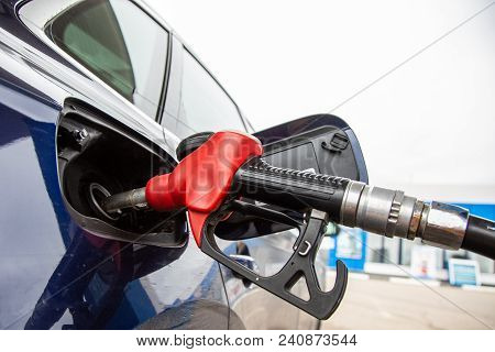 Fuelling Gun Inserted Into The Tank Of Blue Car At The Petrol Station