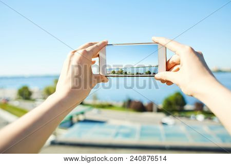 First Person View Of Woman Photographing A Cityscape With River Side On Mobile Phone