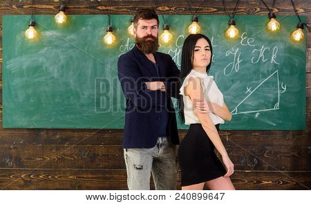 Partners Concept. Man With Beard And Sexy Girl Teacher Stand In Classroom, Chalkboard On Background.